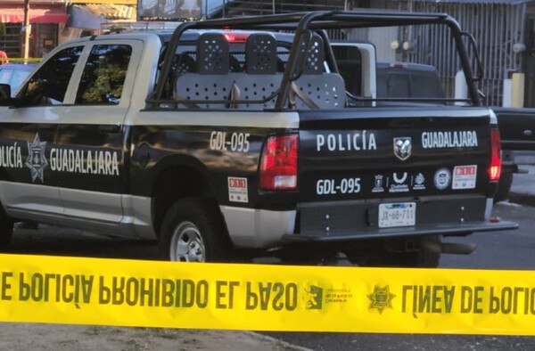 Patrulla de la Policía de Guadalajara con policías apoyados en el cofre dentro de un área acordonada por una cinta policiaca amarilla