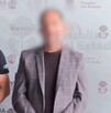 Un hombre siendo detenido, con la cara censurada con blur y con esposas en las manos en medio de dos policías de Jalisco con armas largas