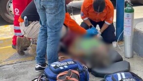 Paramédicos bridando atención médica a una paciente tumbada en el suelo con un tanque de oxígeno a un lado