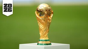 El trofeo de la Copa Mundial de la FIFA sobre una base blanca y al fondo una cancha de fútbol