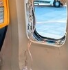 Ventanilla de un avión completamente rota con tubos de las máscara de oxígeno desplegadas en medio de los asientos
