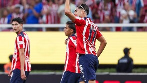 Ricardo Marín, futbolista de las Chivas del Guadalajara levantando el puño con otros jugadores caminando desenfocados en el fondo en el Estadio Akron