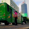 Camión del transporte público en Guadalajara con una mujer con cubrebocas a un lado y los hoteles RIU y Holiday Inn vistos en el fondo