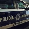 Vista del costado de una patrulla de la Policía de Zapopan estacionada en medio de una calle con casas a los costados