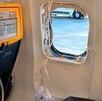 Ventanilla de un avión completamente rota con tubos de las máscara de oxígeno desplegadas en medio de los asientos