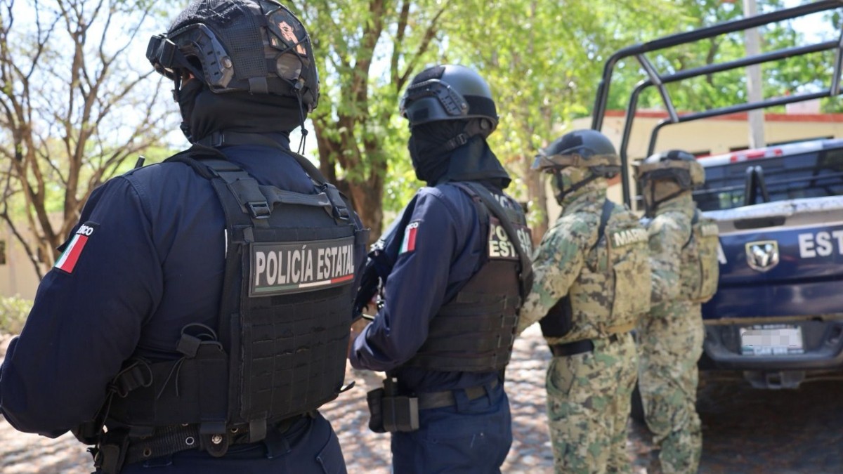 Agentes de la Policía de Colima y militares de la Secretaría de Marina vistos de espaladas al lado de una patrulla del estado
