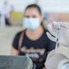 Preparación de vacuna y al fondo una mujer que espera la aplicación