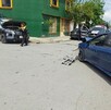 Se observan unos carros y unas personas de pie en la víc pública.