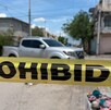 Se observa una cintilla amarilla que dice Precaución y una camioneta blanca al fondo.
