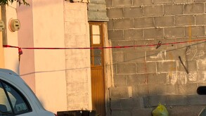 Se observa una puerta color café de una casa y una cintilla amarilla de precaución.