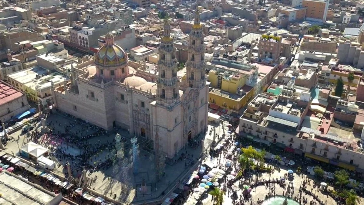 Vista aérea de la catedral y la plaza principal en la zona centro de San Juan de los Lagos con casas, edificios y personas alrededor