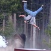 Bisonte embistiendo y arrojando varios metros en el aire a un adulto mayor en el parque de Yellowstone con árboles y una camioneta blanca alrededor