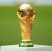 El trofeo de la Copa Mundial de la FIFA sobre una base blanca y al fondo una cancha de fútbol