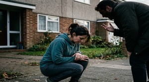 Se observa una mujer agachada y un hombre gritándole, que está también agachado.