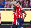 Ricardo Marín, futbolista de las Chivas del Guadalajara levantando el puño con otros jugadores caminando desenfocados en el fondo en el Estadio Akron