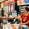 Cliente realizando un depósito en efectivo con una cajera dentro de un Oxxo.