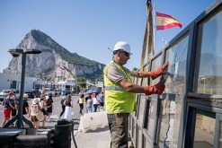 Con el Peñón de Gibraltar de fondo, varios trabajadores desmantelan un puesto de control fronterizo español que separaba de España el territorio británico