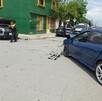 Se observan unos carros y unas personas de pie en la víc pública.