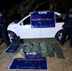 Dos oficiales de la Policía Regional vistos de espaldas resguardando un auto Volkswagen Jetta blanco, una bolsa con drogas y equipo táctico en el suelo
