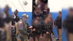 Policías de la Fiscalía de Jalisco sosteniendo armas largas mientras resguardan a internos de un anexo con los rostros censurados con blur