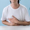 Fotografía de una persona con dolor de estómago y la bacteria que lo causa
