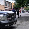 Se observa una cinta roja de precaución, varios autos estacionados sobre la vía pública.
