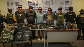 cinco hombres detenidos custodiados por policías y presentados con armas decomisadas