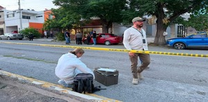 Se observa a un hombre y una mujer en la calle, una mujer vestida con traje blanco de perito y una cinta amarilla de precaución.