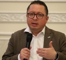 Hombre de lentes y cara gorda hablando ante un micrófono.