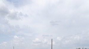 Se observa un sacerdote vestdo con túnica negra y una camioneta blanca al fondo volcada.