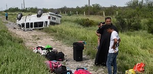 Se observa un sacerdote vestdo con túnica negra y una camioneta blanca al fondo volcada.