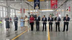 Se observa a mujeres y hombres de pie sosteniendo un listón rojo.