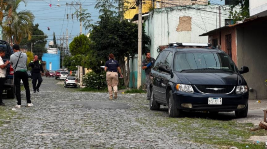 Agentes de Ciencias Forenses y policías de Jalisco en medio de una calle con una camioneta negra estacionada en el sitio