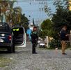 Policía de Jalisco con un arma larga en medio de la calle con una patrulla y un elemento de Ciencias Forenses a los lados