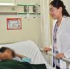 Doctora ginecoobstetra al lado de una camilla con una paciente menor de edad con la cara censurada con blur en clínica del IMSS de Nayarit