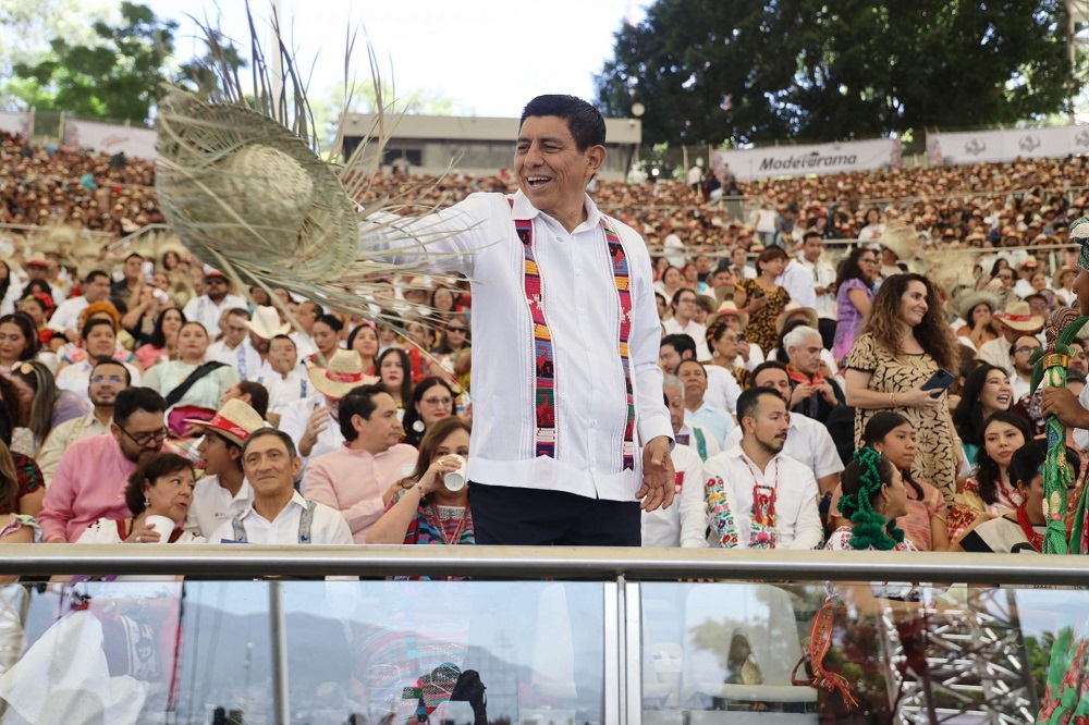 Hombre lanzando su sombrero ante un escenario en Oaxaca.