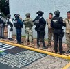 Policía federales y estales con el Ejército Mexicano vistos de espaldas durante detención de 11 criminales con armas y drogas en el suelo
