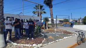 Se observa a varias personas de pie frente a un letrero que dice Palliser.