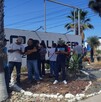 Se observa a varias personas de pie frente a un letrero que dice Palliser.