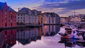 Un puerto de Noruega con casas y algunos barcos pequeños