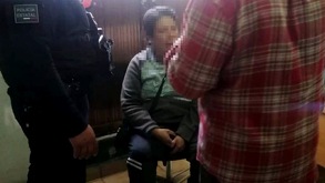 Mujer sentada en una silla mientras es cubierta por un policía y un civil.