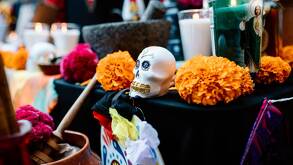 Una ofrenda de Dia de Muertos con una veladora y una calavera de azúcar