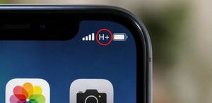 Símbolo de H+ entre el ícono de la batería y barras de señal en la esquina de la pantalla de un teléfono Iphone con íconos de cámara y galería debajo