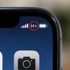 Símbolo de H+ entre el ícono de la batería y barras de señal en la esquina de la pantalla de un teléfono Iphone con íconos de cámara y galería debajo