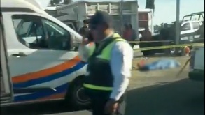 Policía hablando por teléfono junto al cuerpo de una persona muerta.