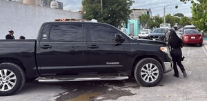 Se observa una camioneta negra estacionada en la vía pública y hay una cinta amarilla de precaución.