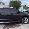 Se observa una camioneta negra estacionada en la vía pública y hay una cinta amarilla de precaución.