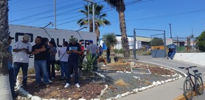 Se observa a varias personas de pie frente a un letrero que dice Palliser.