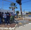 Se observa a varias personas de pie frente a un letrero que dice Palliser.