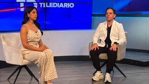 Se observa a una mujer y un hombre sentados con un fondo azul.